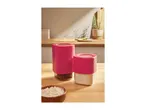 Two pink kitchen storage containers, one with beans and one with flour, on a wooden counter.
