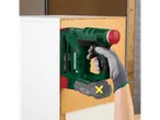 Homem com luvas usa um agrafador verde sem fios para fixar um painel de madeira a um móvel branco.