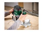 Person using a plunge router to cut a circular groove into a wooden board.