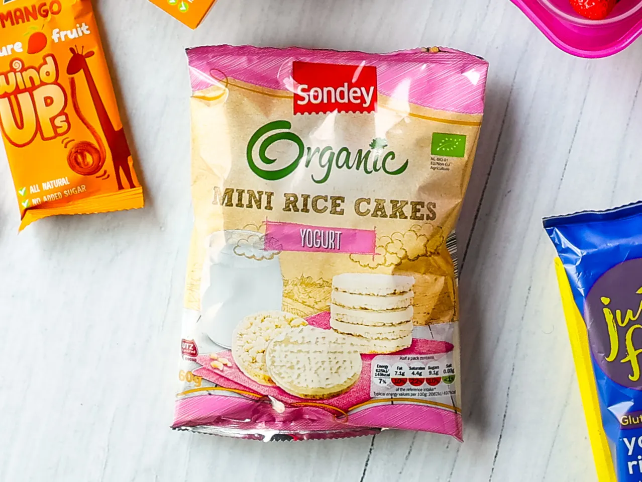 A bag of Sondey Organic Mini Rice Cakes with yogurt flavor, next to a Mango Fruit Wind Up snack.