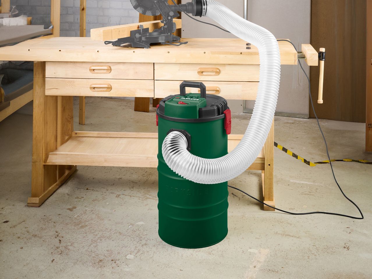 PARKSIDE® Chip & Dust Extractor connected to a miter saw via a hose, in a workshop setting.