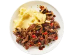 Diced beef steak with mashed potatoes, mushrooms, and vegetables on a white plate.