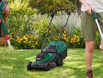 A person using a lawnmower and another holding a grass trimmer in a sunny garden.