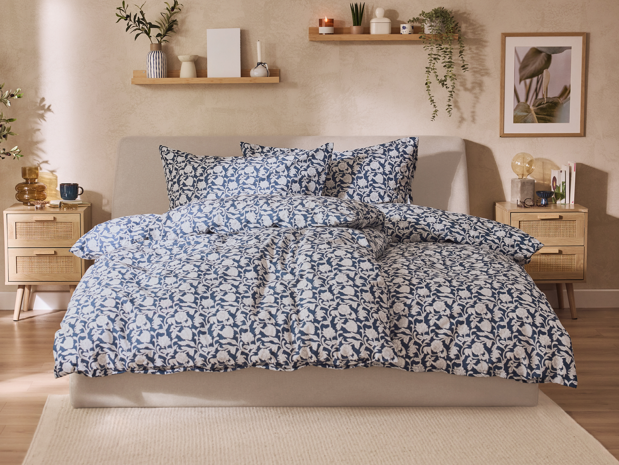 Спалня с легло със синьо-бял спален комплект, нощни шкафчета и рафтове с декорации.