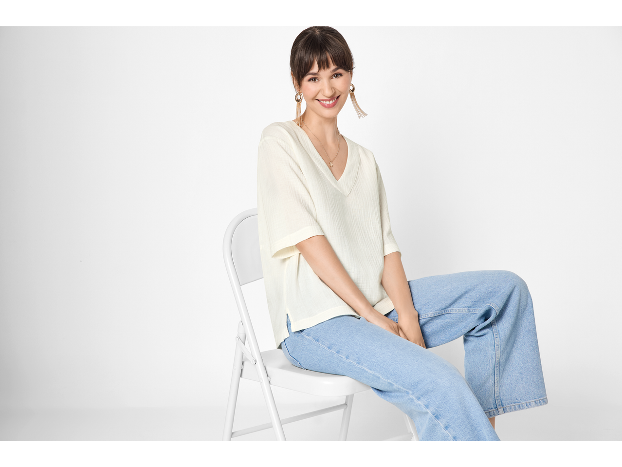 Femeie în bluză de muselină ESMARA și blugi, zâmbind la cameră