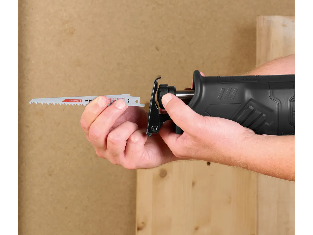 A person inserts a jigsaw blade into a black jigsaw.