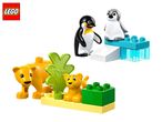 Toy penguins on an ice block and toy lions with green foliage on a yellow base.