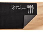Black Kitchen Runner with 'Kitchen' text and cutlery design on a wooden floor.
