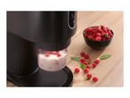 Black ice cream maker with raspberries and mint on a wooden surface.