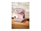 Pink espresso machine with a gauge, portafilter with coffee grounds, and coffee beans.