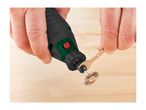 Hands attaching a wire brush accessory to a rotary tool with a small wrench.