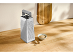 Ralador de cozinha Silvercrest® com noz-moscada ralada e nozes inteiras numa tábua de madeira.