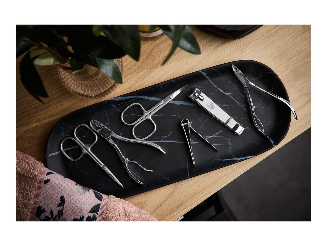 Manicure set with nail clippers, cuticle nippers, and scissors on a black marble tray.