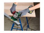 A person using a cordless angle grinder to cut a metal bar on a workbench.