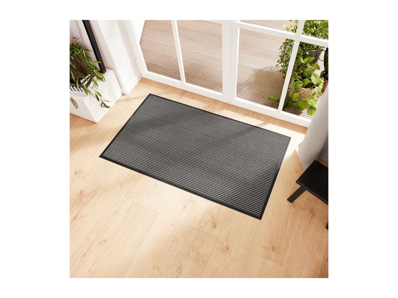 Striped doormat on a light wood floor in front of glass doors.