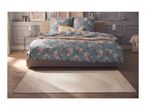 Bedroom with a bed featuring blue floral bedding, a beige rug, and two bedside tables.