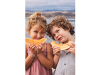 Two happy children holding and eating slices of fresh cantaloupe melon outdoors.