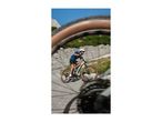 Man in blue shirt and black shorts riding a mountain bike on a paved road.