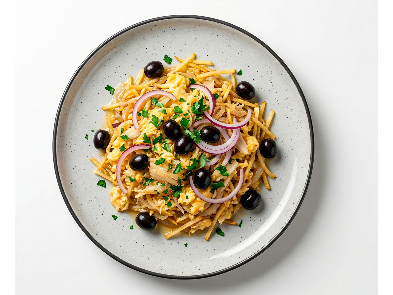 Bacalhau à Brás com bacalhau desfiado, ovos mexidos, azeitonas e cebola roxa num prato.