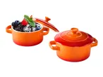 Two orange ceramic mini cocottes, one with a chocolate dessert and berries, one closed.