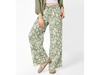 Woman wearing green floral wide-leg trousers, a white crop top, and a green jacket.