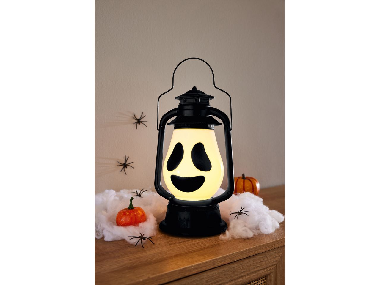Lanterna di Halloween con faccia da fantasma, ragnatele finte, ragni e zucche decorative.
