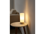 O lampă de masă modernă luminează o măsuță de cafea lângă o canapea.