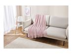 A living room with a light gray sofa, pink throw blanket, and a white rug.