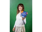 A woman smiling and holding a Juspy Collagen + Protein cacao superfood powder blend.