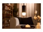Warmly lit living room with a hanging pendant light, sofa, and decorative vase.
