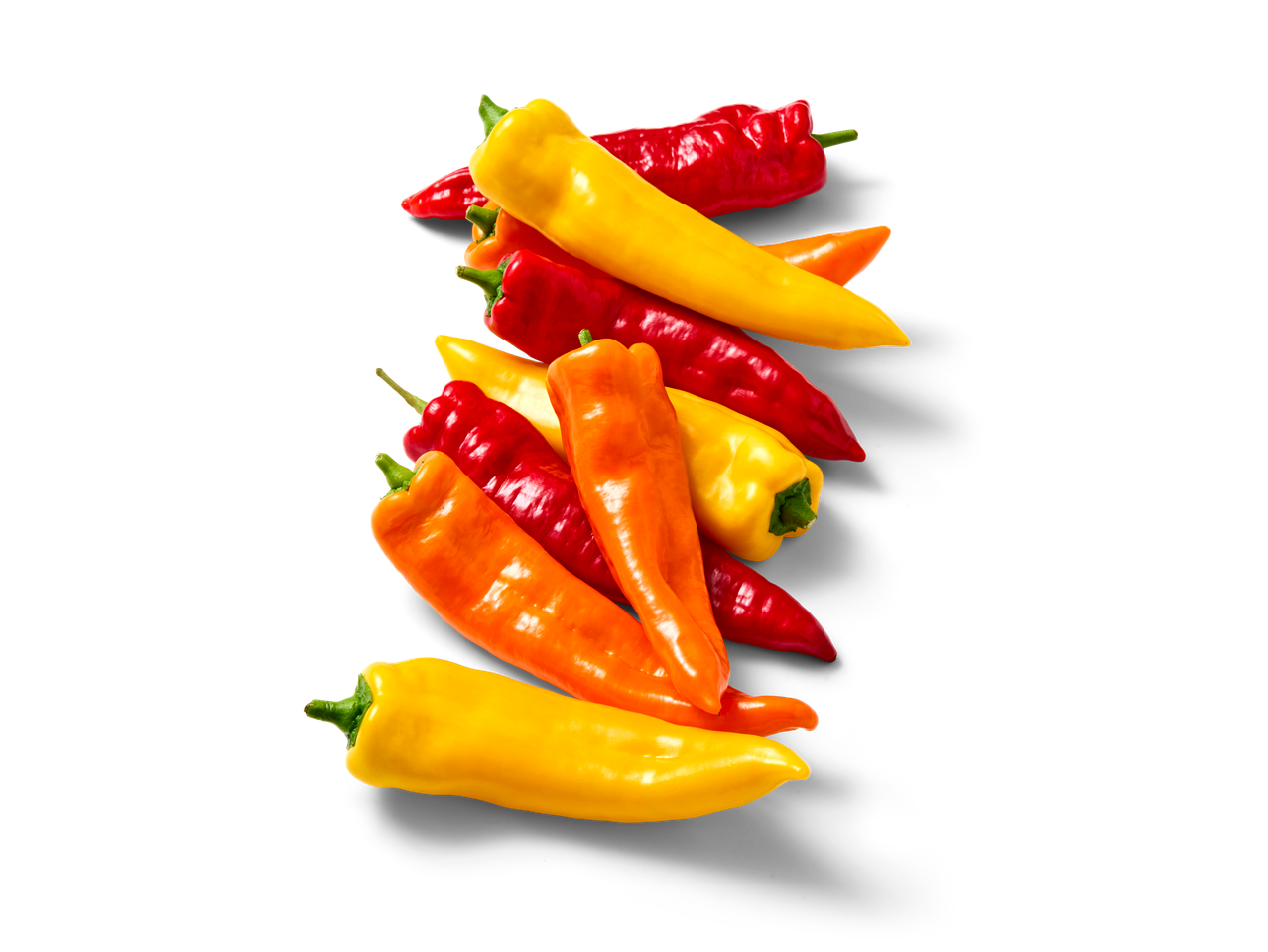 Een stapel kleurrijke paprika's in geel, oranje en rood tegen een zwarte achtergrond.