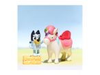 Bluey toy standing on a hay bale next to a unicorn toy with a pink saddle.