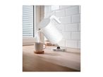 White electric kettle pouring hot water into a mug on a wooden kitchen countertop.