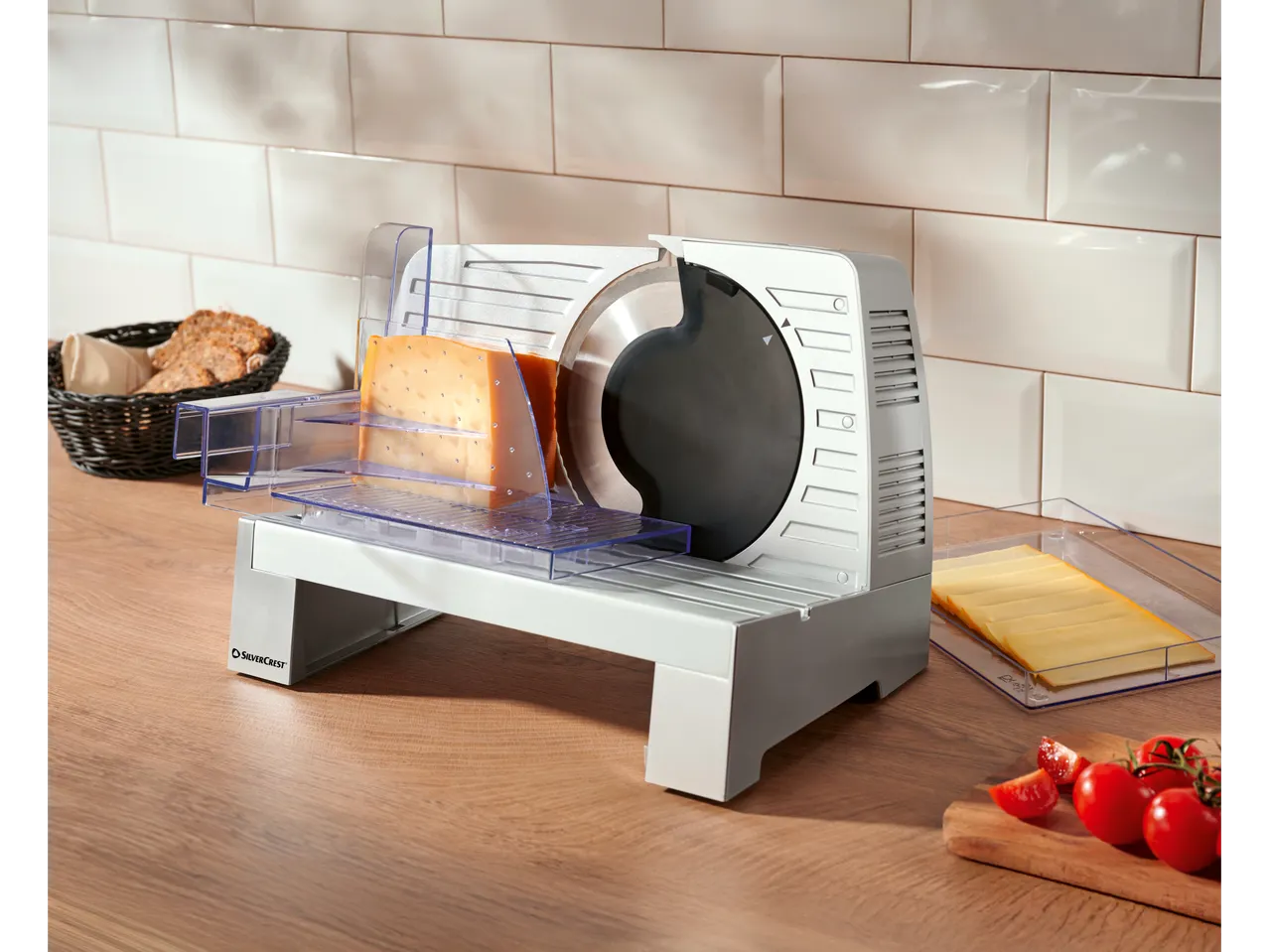 SILVERCREST® Electric Multi-Purpose Slicer with cheese, bread, and tomatoes on a wooden counter.