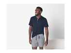 Man in a navy short-sleeved Henley shirt and black and white checkered shorts.