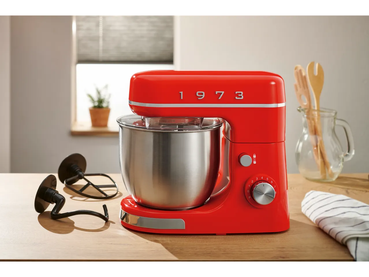 Piros SILVERCREST® 650W álló mixer rozsdamentes acél tálal és kiegészítőkkel egy fa asztalon.