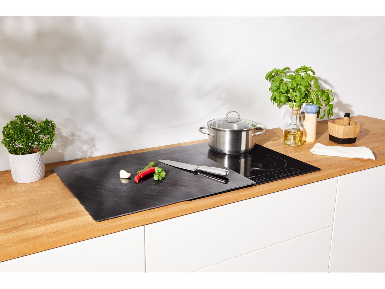 Moderna kuhinja z indukcijsko kuhalno ploščo in skrilavčevo ploščo.