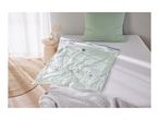 Vacuum storage bag with a light green duvet inside, on a bed with a green pillow.