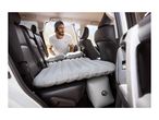 Man setting up an inflatable car mattress with pillows in the back of an SUV.