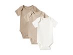 Three baby bodysuits in beige and white, arranged diagonally.