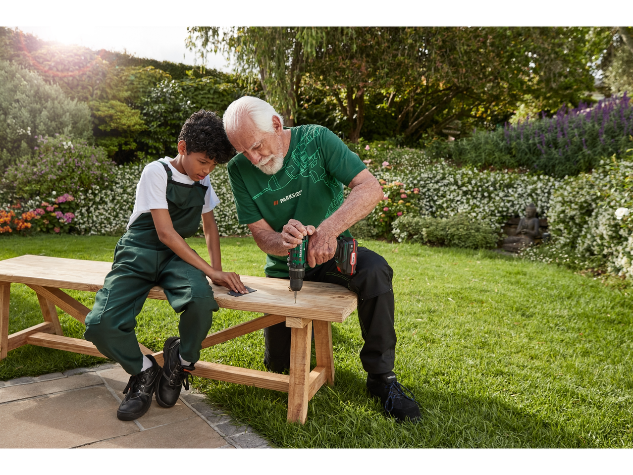 Older man and boy building a wooden bench using a Parkside drill.