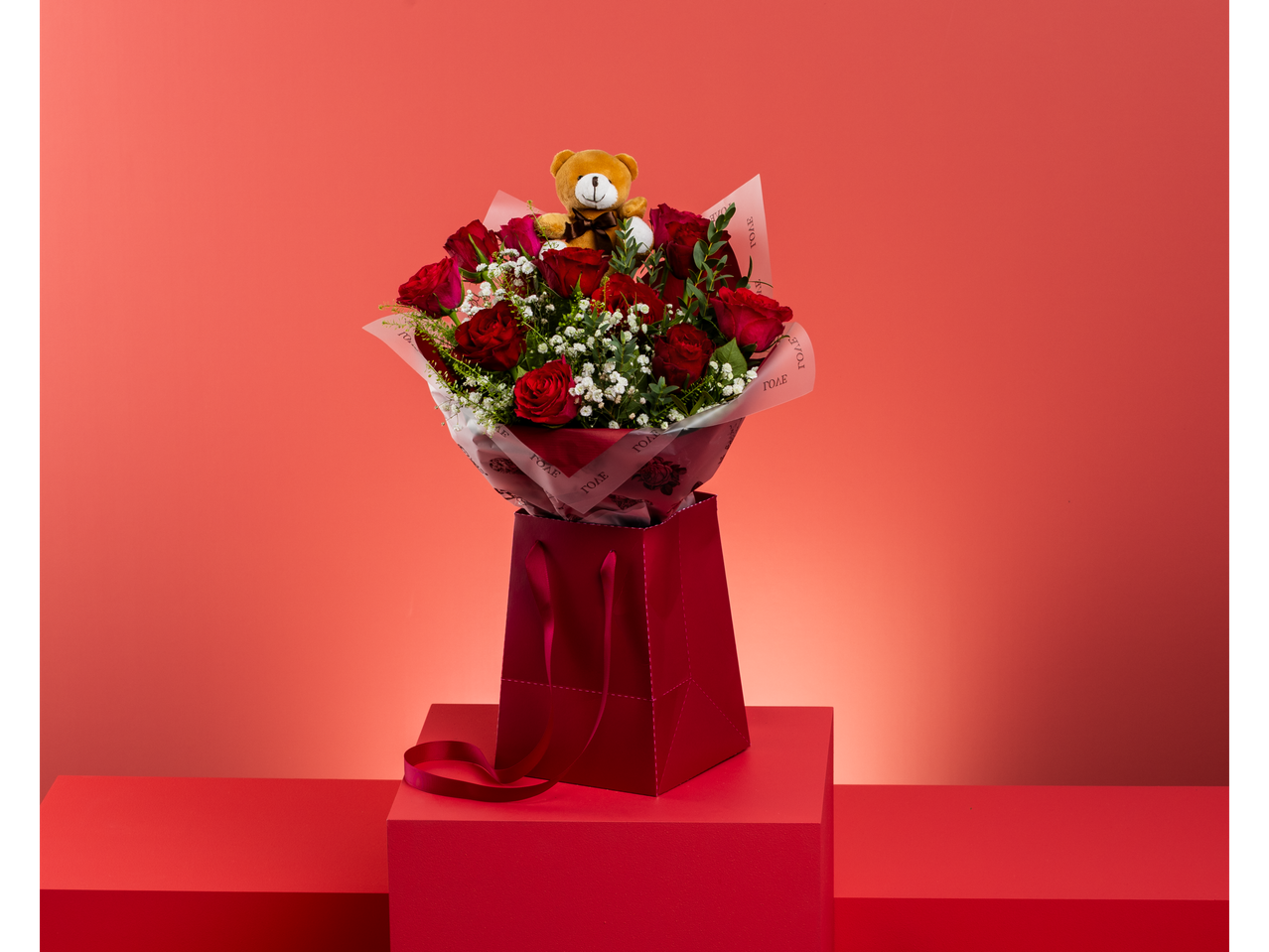 Red roses bouquet with a teddy bear in a gift bag on a red background
