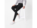 A woman in a striped sweater and black leggings sits on a white stool.