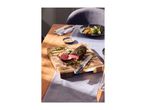 Cooked beef tenderloin with herbs on a wooden cutting board, with a knife and side dishes.