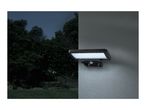 A solar-powered LED security light mounted on a wall at night, illuminating the area.