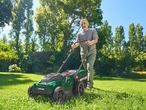 Egy férfi Parkside fűnyíróval nyírja a füvet a kertjében.