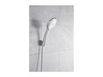 Chrome shower head spraying water against a grey tiled wall.