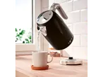 Black Silvercrest kettle pouring water into a cup on a wooden counter.