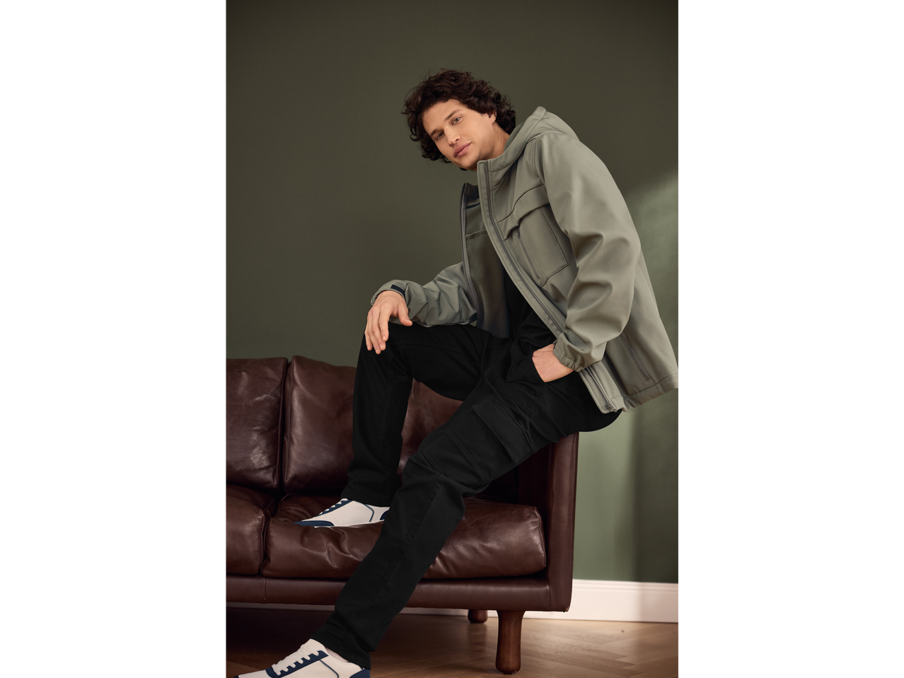 Vyras sėdi ant sofos su Esmara marškinėliais ilgomis rankovėmis ir striuke.