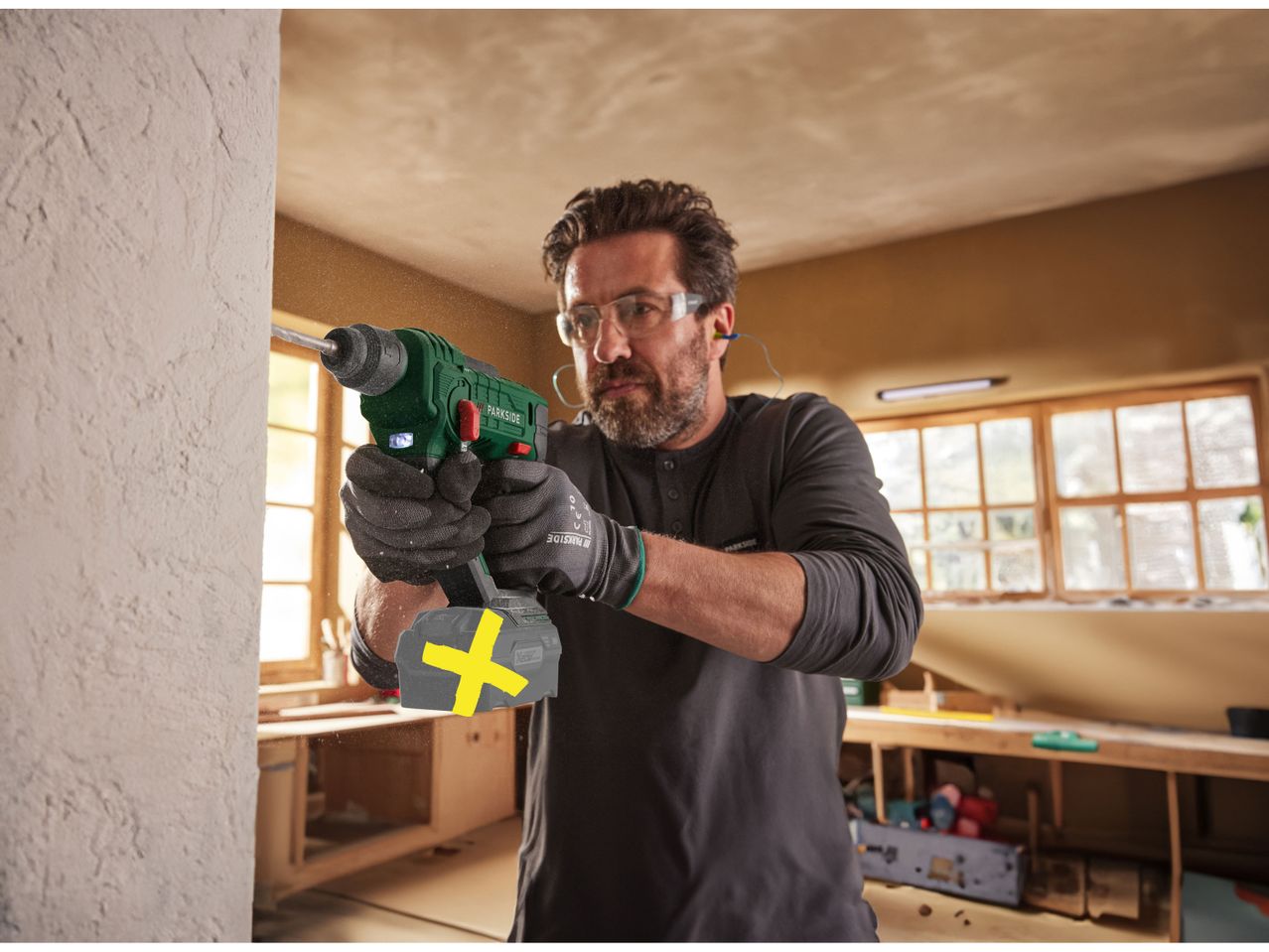 A man uses a Parkside Cordless Hammer Drill to make a hole in a wall.